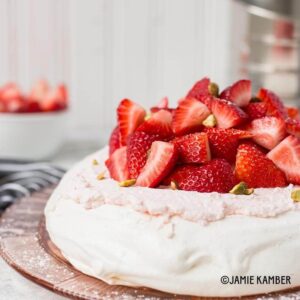 Meringue cake topped with fresh strawberries and pistachios.