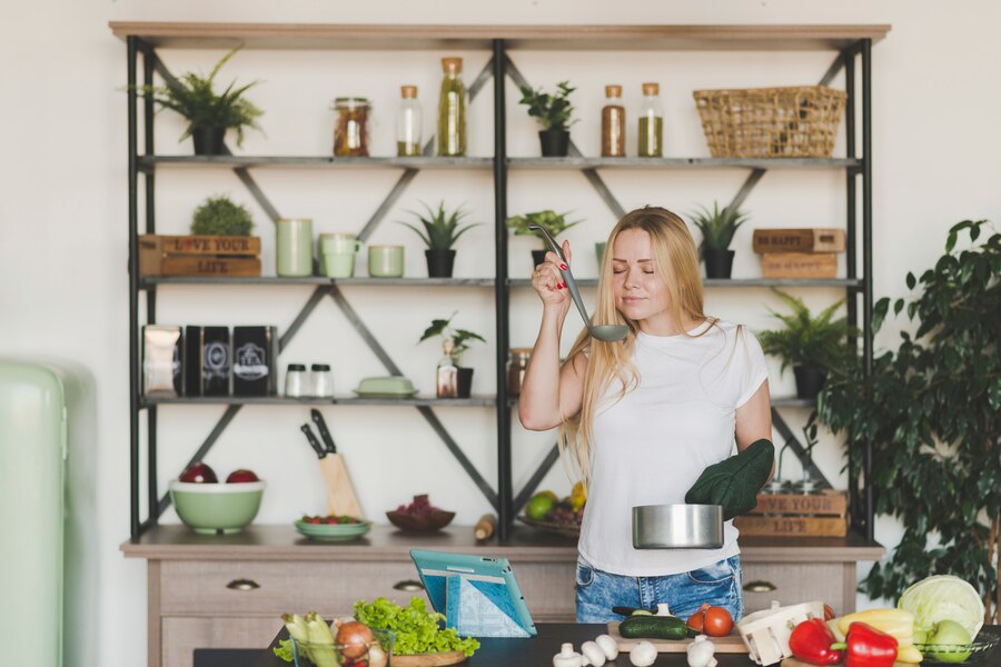 blonde-young-woman-smelling-soup-from-ladle-kitchen